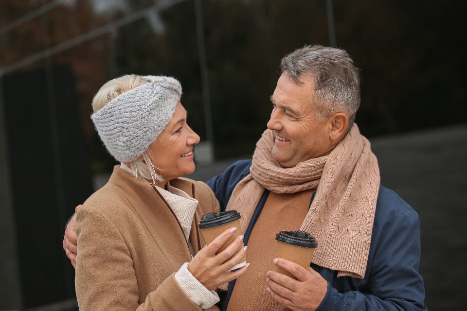A couple in their fifties laughing together over coffee